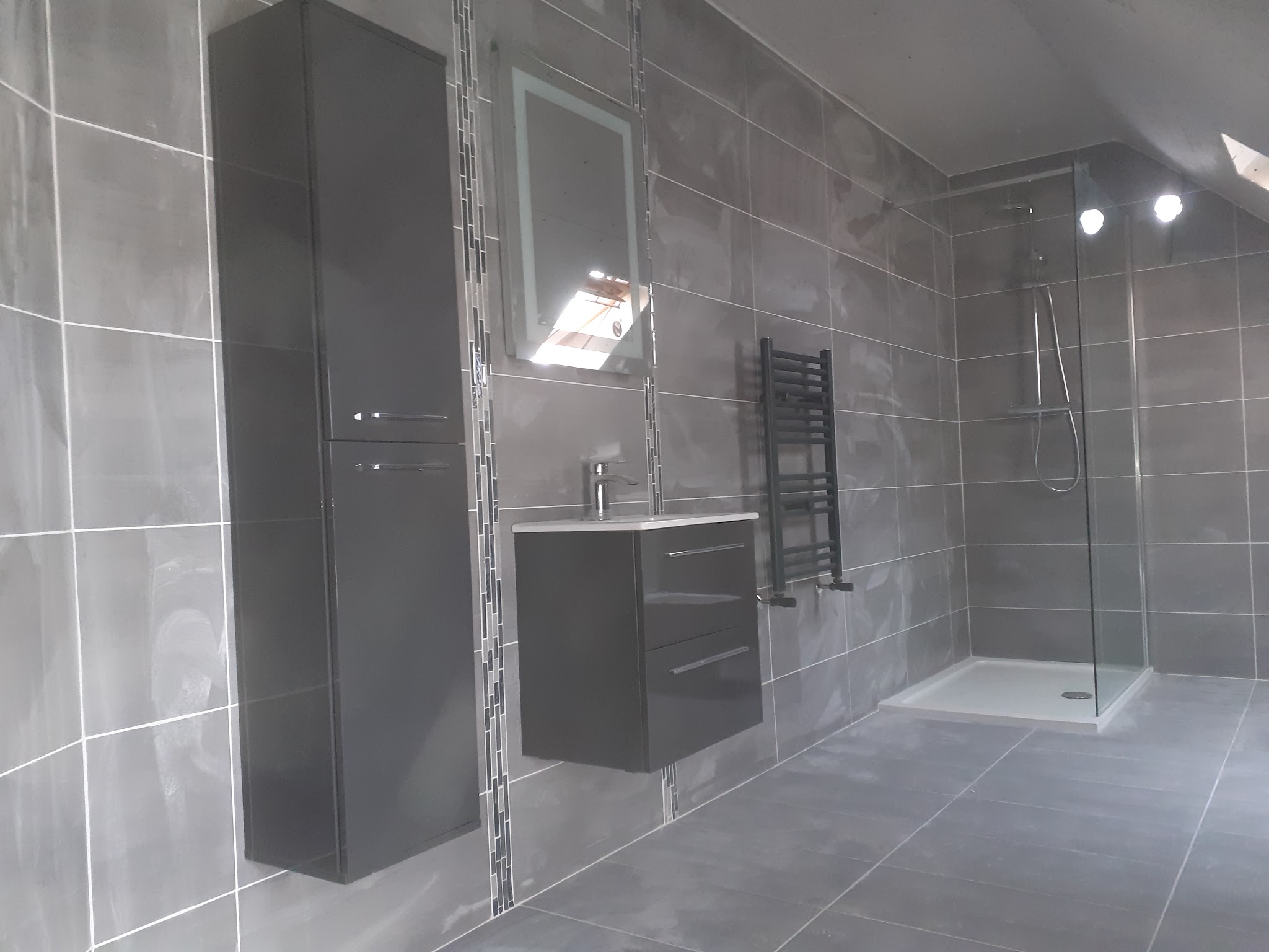 Grey-tiled bathroom with a walk-in shower, wall-hung vanity, tall unit and towel rail