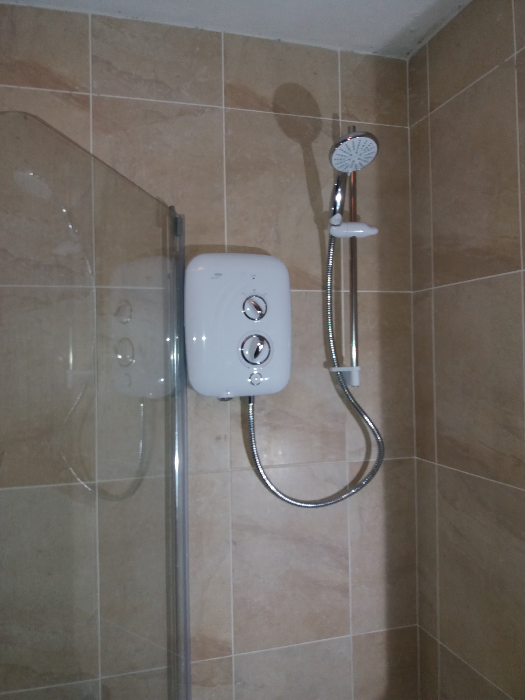 Electric shower fitted in a tiled shower enclosure