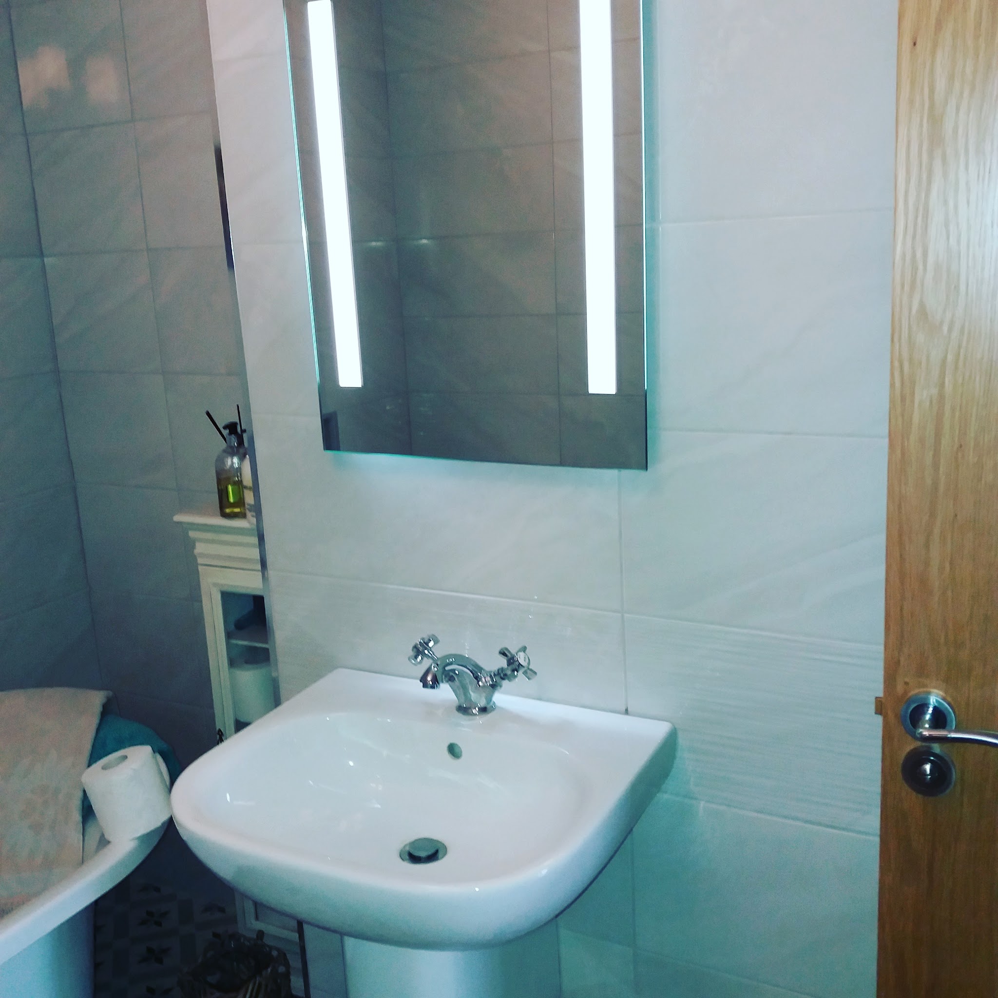White pedestal basin under a backlit LED mirror