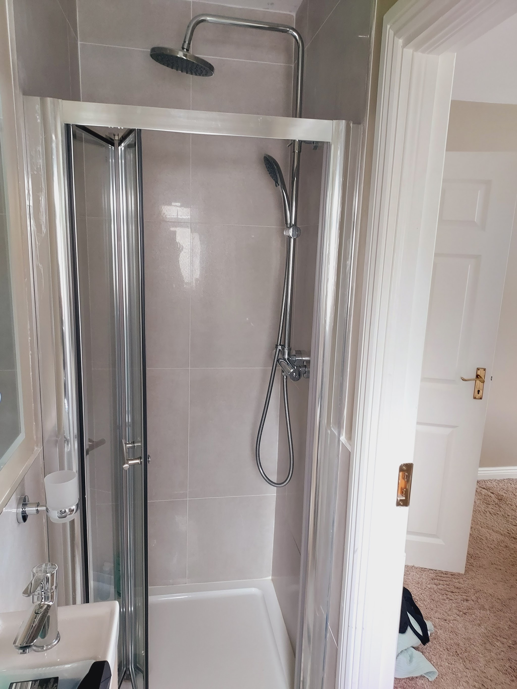 Shower enclosure with a bifold door and a riser rail shower