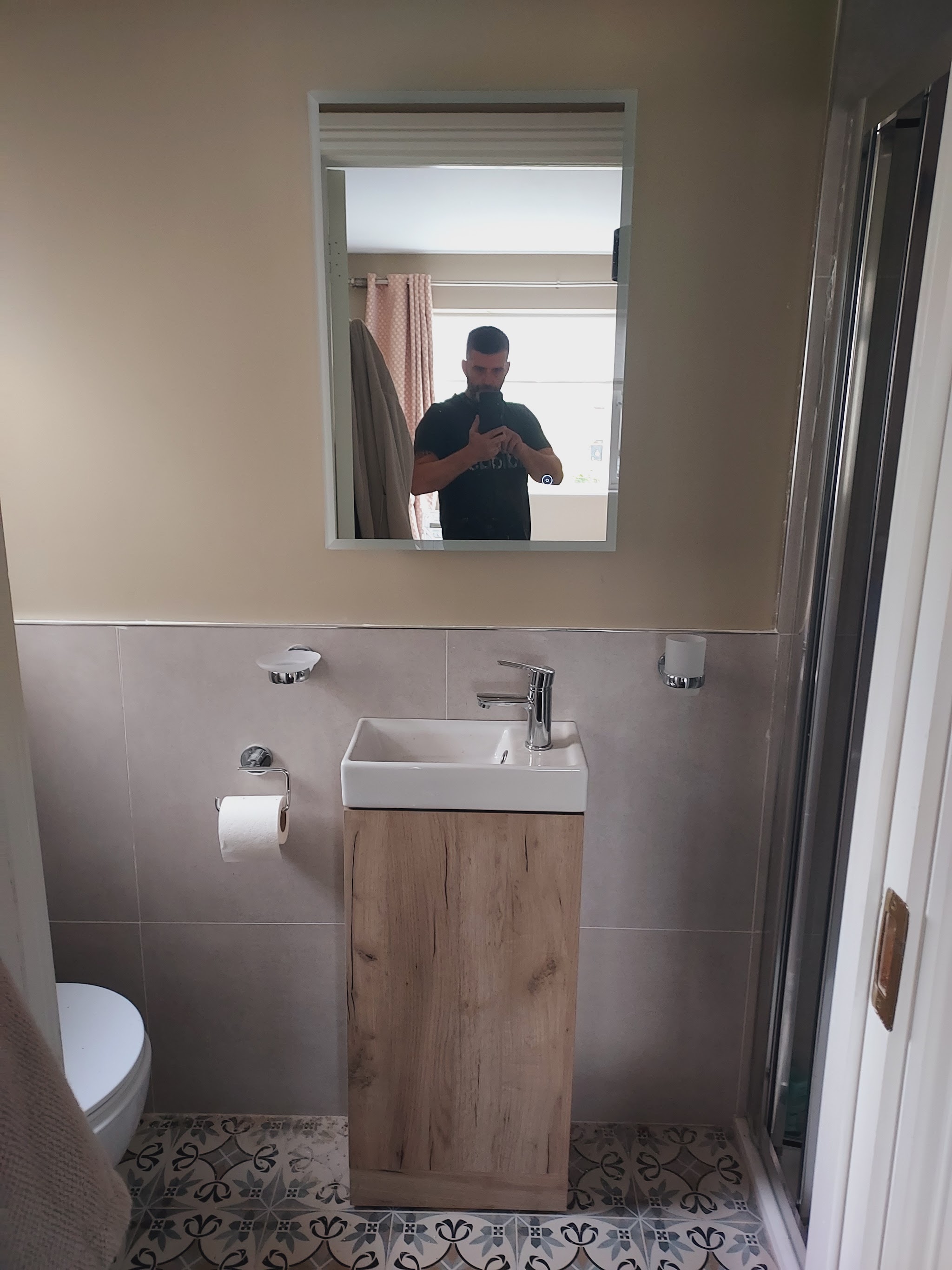 Small en-suite with an oak vanity unit, mirror and patterned floor tiles